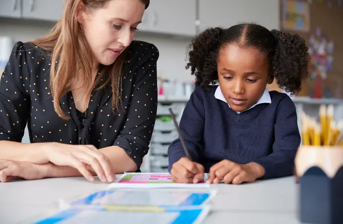 Teacher and pupil sitting together in a classroom